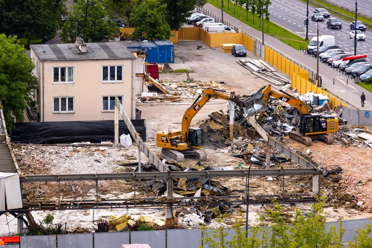 Dwa koparki pracują przy rozbiórce budynku. Zastanawiasz się, ile kosztuje rozbiórka domu?