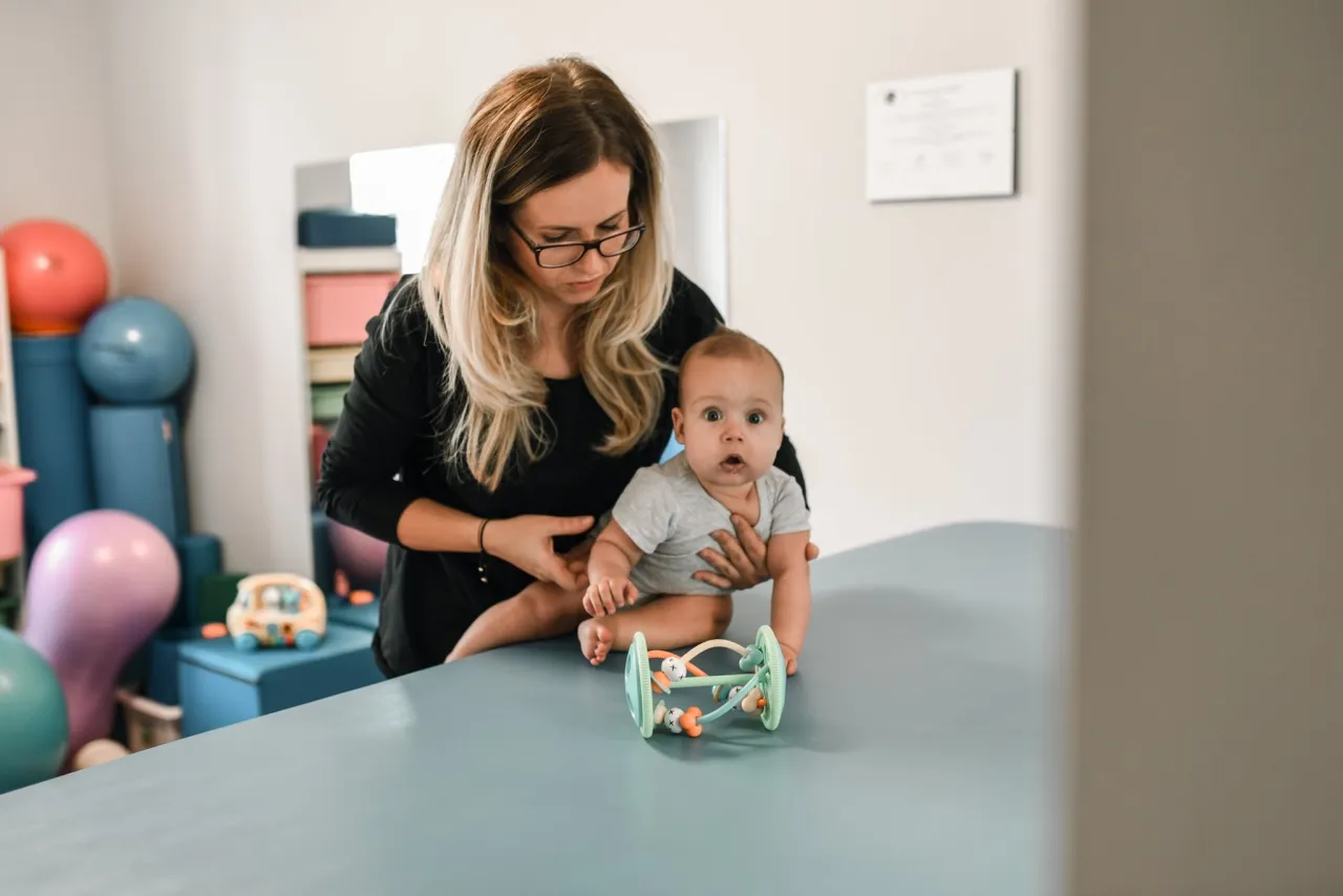 Niemowlę na brzuchu, dziecko ćwiczące, fizjoterapeuta z niemowlęciem