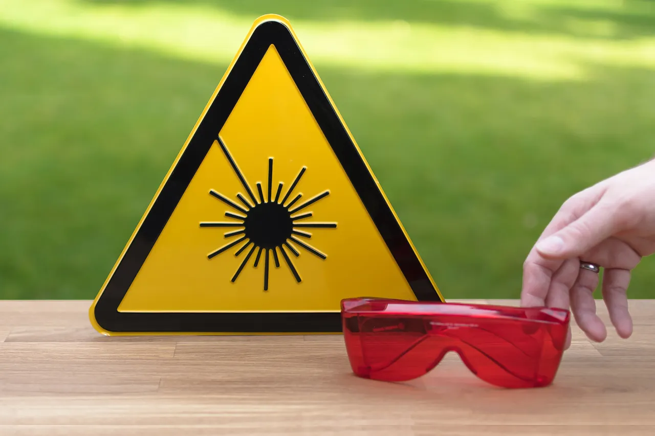 Nastolatka z gładką sk&oacute;rą, zadowolona, ale w tle delikatnie zarysowany laser (kontekst bezpieczeństwa)