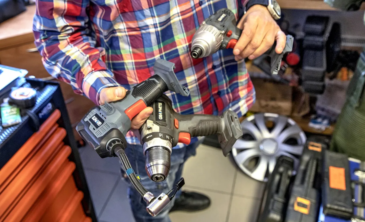 Warsztat samoobsługowy Warszawa: mężczyzna trzyma w rękach wkrętarkę i klucz udarowy, gotowy do pracy.