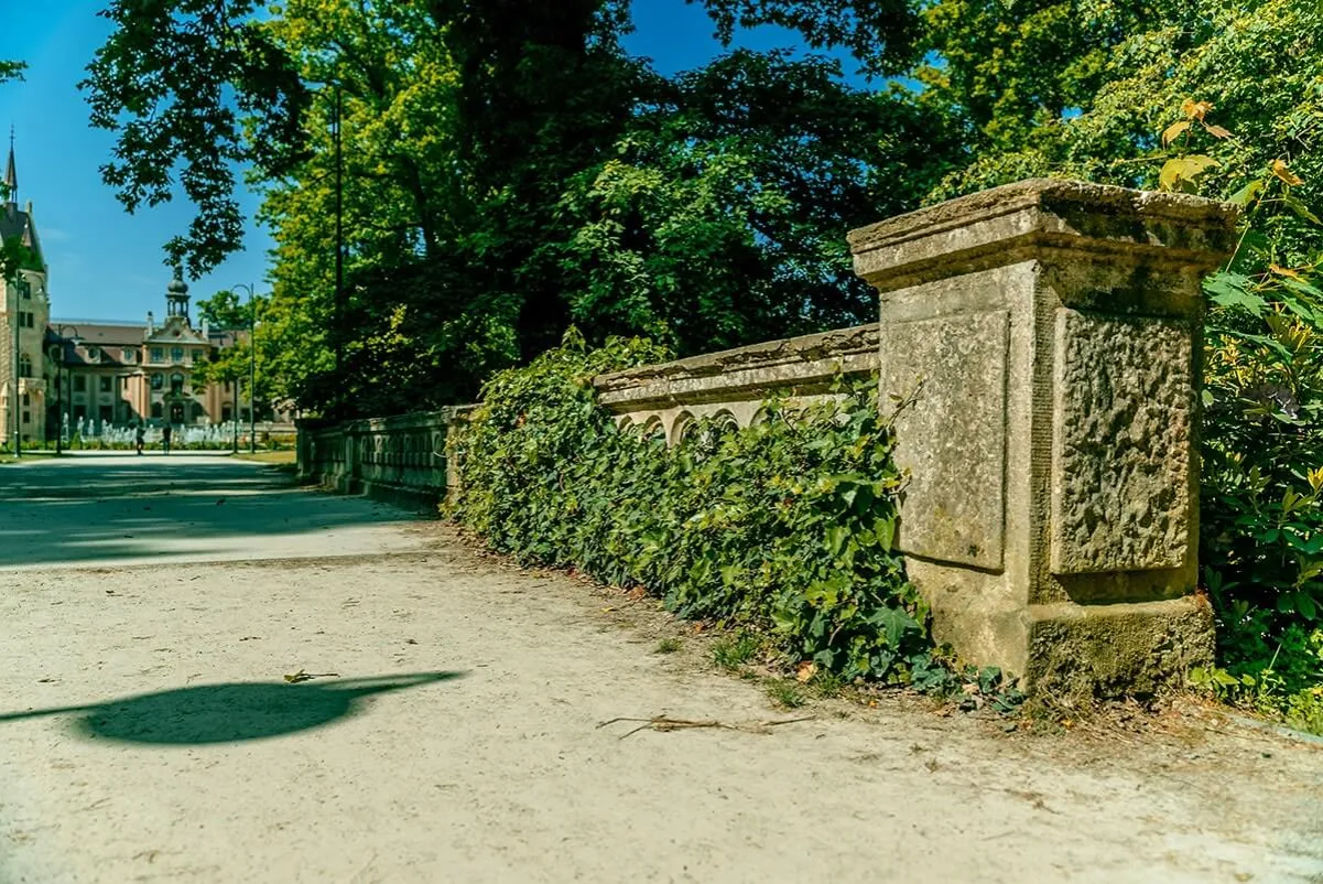 Kamienna balustrada porośnięta bluszczem prowadzi do zamku. Zastanawiasz się, ile trwa zwiedzanie zamku Moszna?