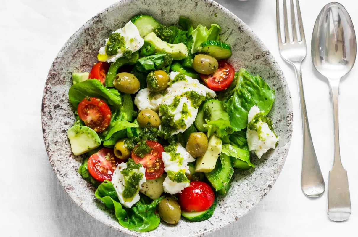 Sałatka z mozzarellą, pomidorkami, ogórkiem i oliwkami, polana sosem z bazylii. Co z niej zrobić? Pyszny obiad!