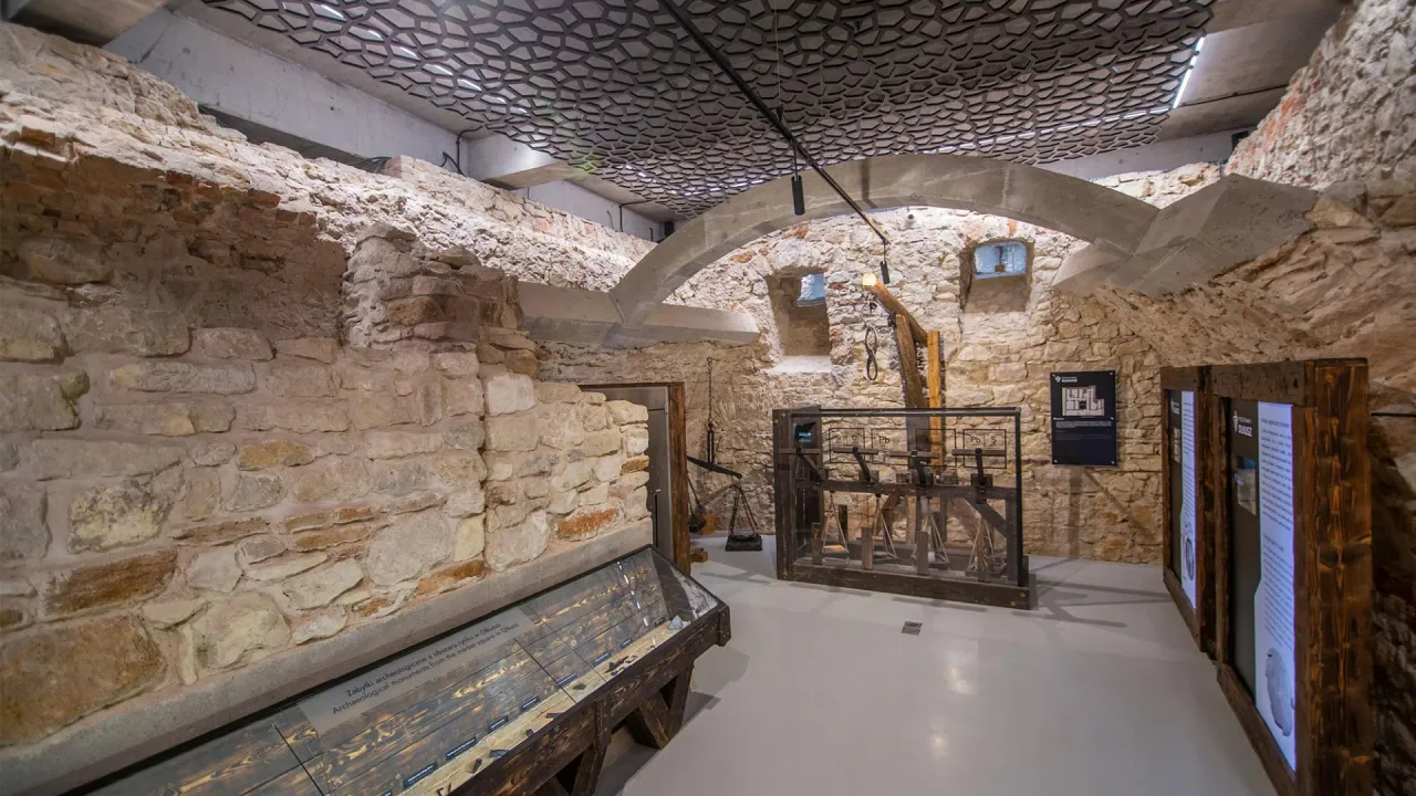 Wystawa w Olkuszu, gdzie kamienne mury opowiadają legendę o mieście. Ekspozycja ukazuje historyczne artefakty i mechanizmy.