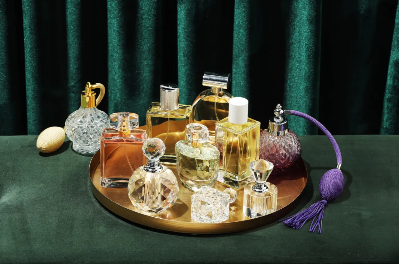 Kolekcja flakon&oacute;w z perfumami, w tym te, kt&oacute;re definiują, czym są perfumy niszowe. Eleganckie szkło i złote detale na tle zielonego aksamitu.