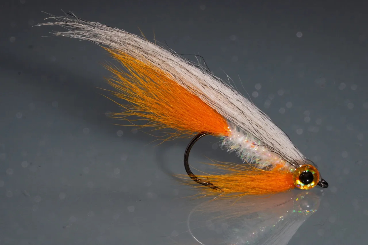 Pomarańczowo-biała mucha wędkarska, imitująca drobną rybkę. Idealna odpowiedź na pytanie, na co najlepiej łowić ryby w trudnych warunkach.