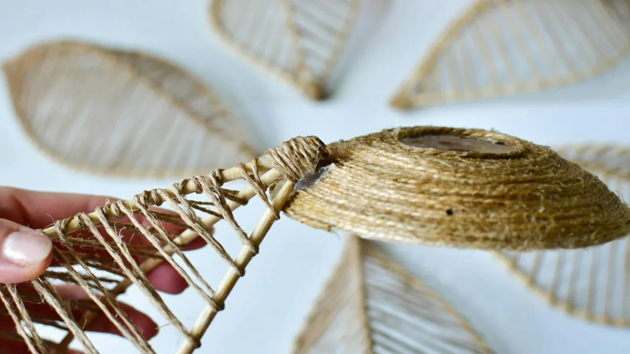 Ręcznie robiony abażur z tkaniny, tworzony przez owijanie sznurka wok&oacute;ł bambusowej konstrukcji.