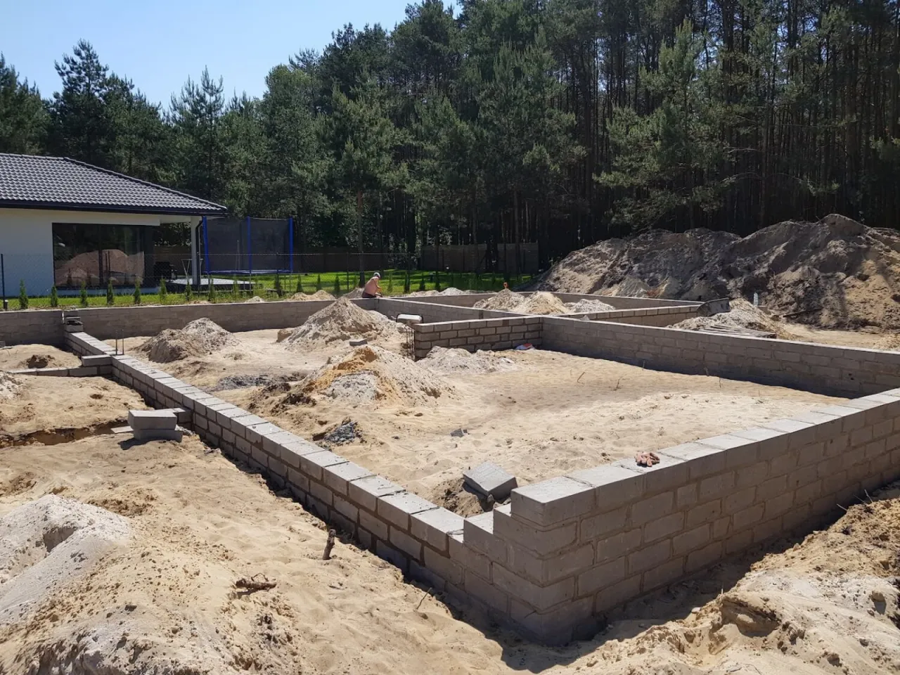 Fundamenty domu w budowie, piasek i bloczki betonowe. To pierwszy etap budowy domu krok po kroku.