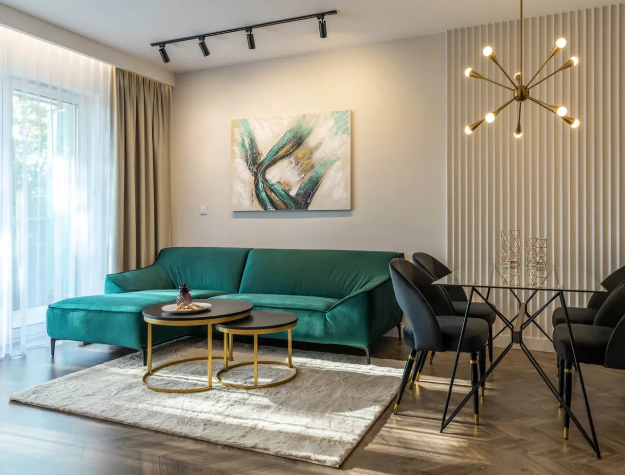 Nowoczesny salon z aksamitną, zieloną kanapą. Inspiracje dla Twojego wnętrza: elegancka jadalnia, sztuka na ścianie i designerskie oświetlenie.