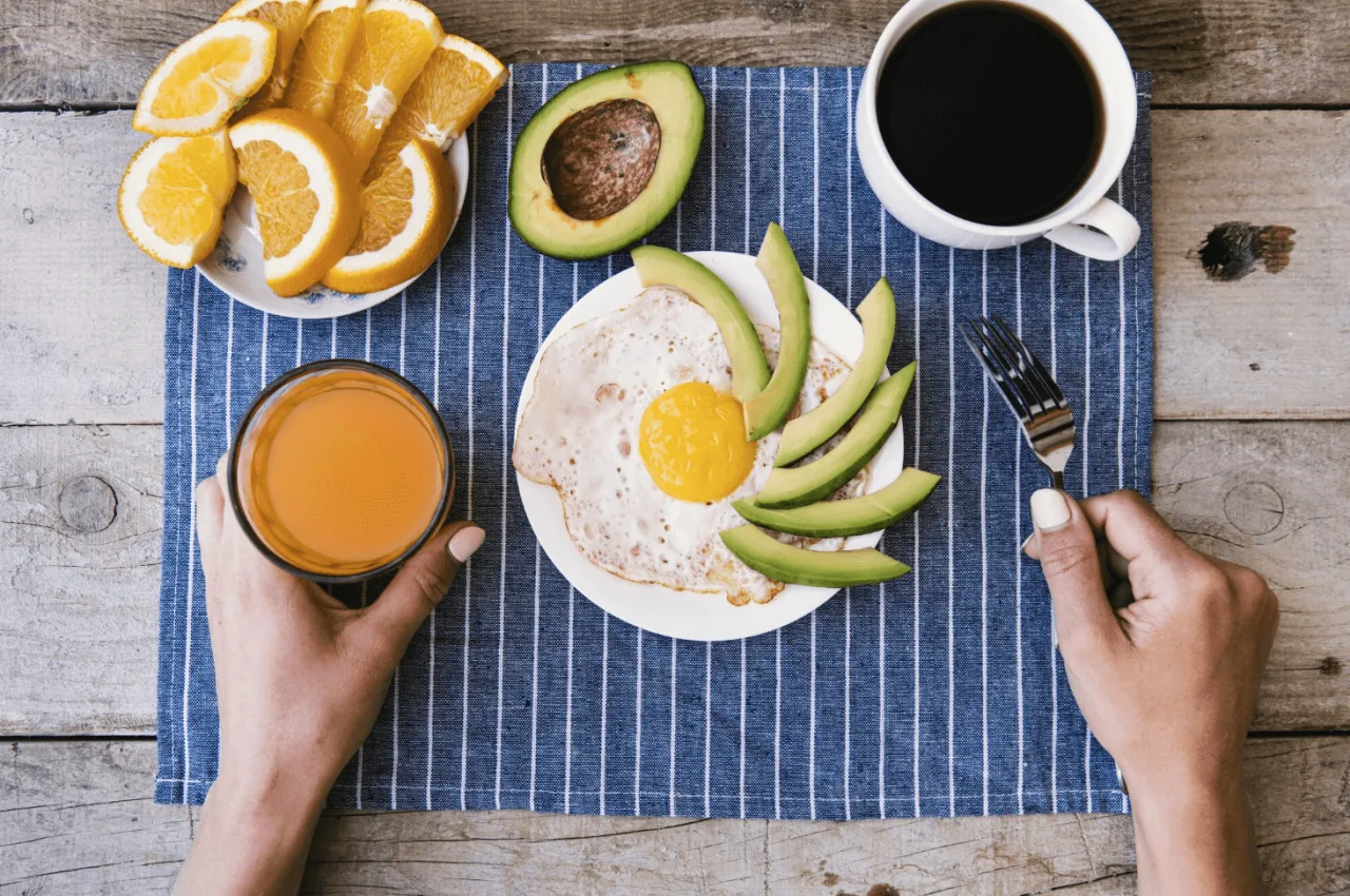 Zdrowe śniadanie z jajkiem sadzonym, awokado, pomarańczami i kawą. Zastanawiasz się, ile kalorii powinno mieć śniadanie?