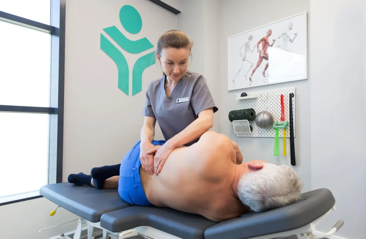 Fizjoterapeuta pomaga pacjentowi z bólem pleców