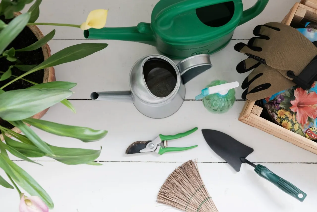 Narzędzia do przesadzania roślin: konewki, sekator, łopatka, rękawice i ziemia. Gotowi na wiosenne prace w ogrodzie!