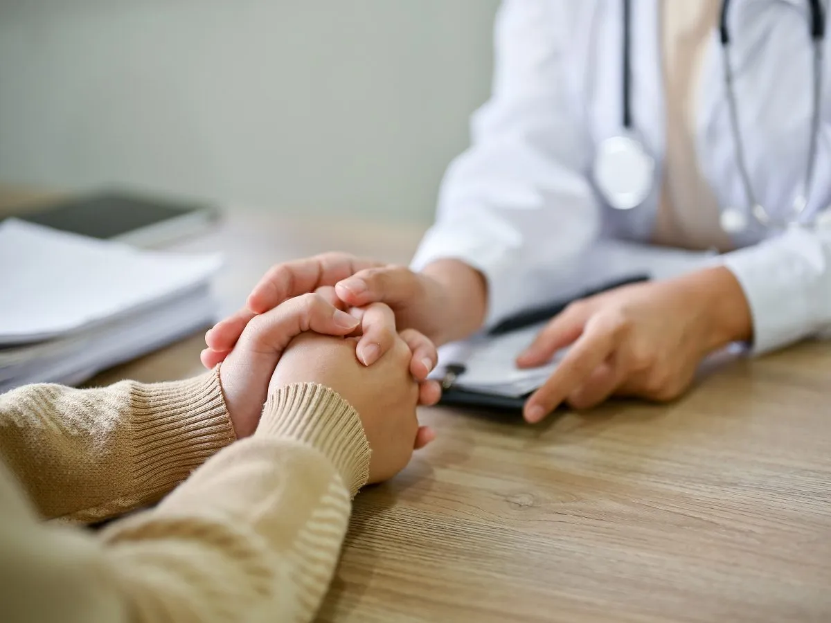 Lekarz uspokaja pacjenta, który martwi się, jak dostać leki na depresję. Dłoń lekarza na dłoni pacjenta.