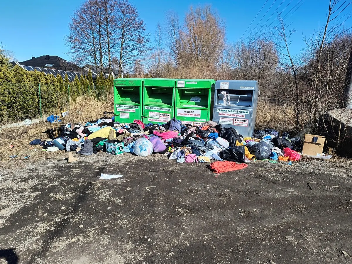 Stosy ubrań i work&oacute;w leżą obok pojemnik&oacute;w na odzież. Ktoś zapomniał, co z wywozem śmieci?