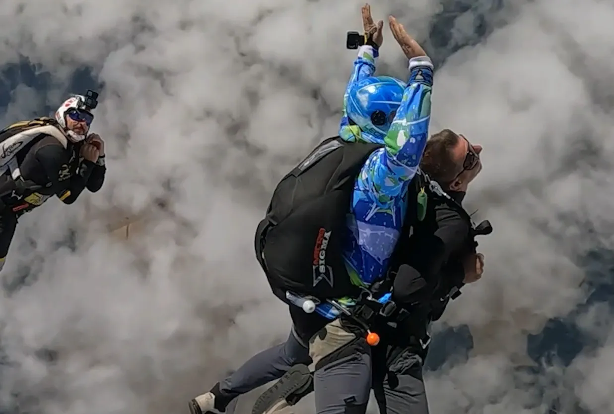 Mężczyzna skaczący ze spadochronem lub jadący sportowym samochodem