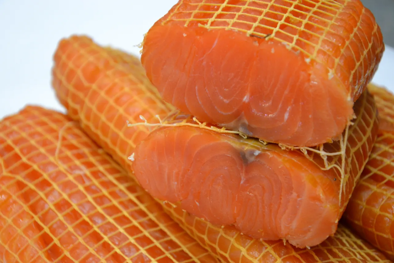 Stek z łososia w siatce, gotowy do pieczenia. Obok leżą polędwice z dorsza, również w siatce.