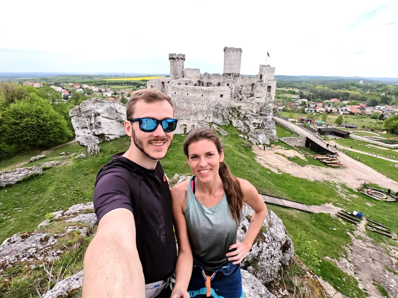 Para co zobaczyć w Zawierciu? Ruiny zamku Ogrodzieniec na skale, z parą turystów na pierwszym planie.