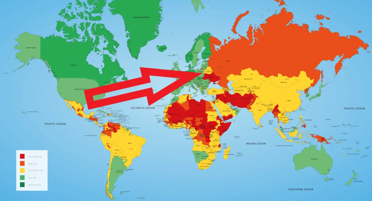Mapa świata z zaznaczonymi strefami ryzyka. Czerwona strzałka wskazuje na USA, które są zielone, co oznacza niskie ryzyko. Czy w USA jest bezpiecznie? Tak, według tej mapy.