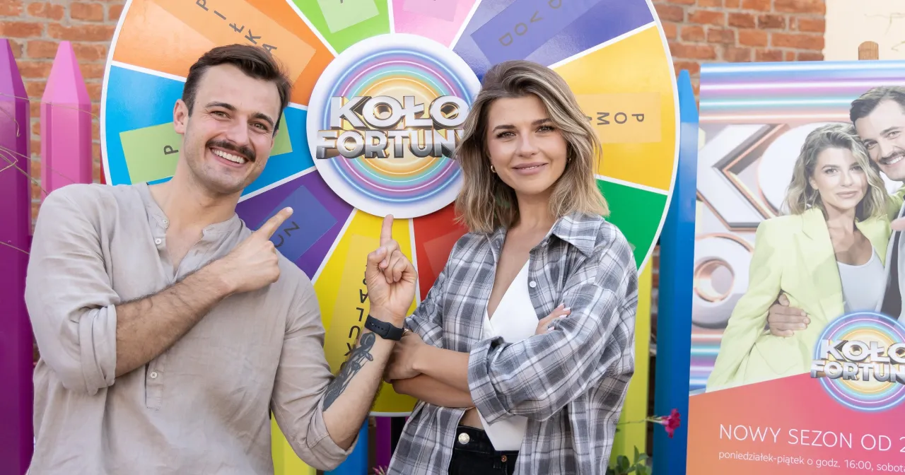 Kto jest nowym prowadzącym Koło Fortuny? Uśmiechnięci prowadzący przy kole gry.