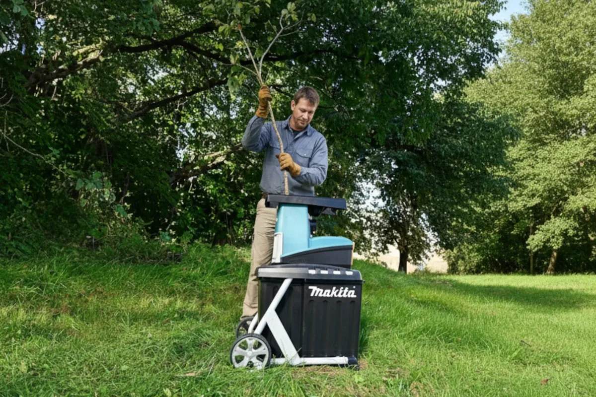 Mężczyzna w rękawicach wkłada gałąź do rozdrabniacza do gałęzi spalinowego Makita.