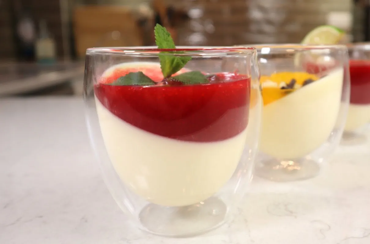 Panna Cotta przepis: kremowy deser z musem malinowym i miętą, w szklanych pucharkach.