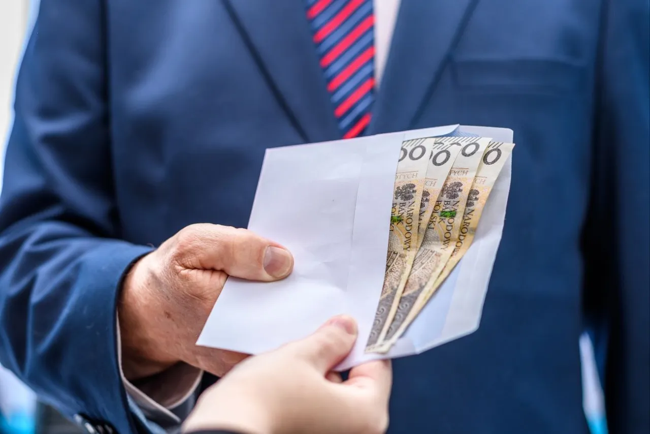 Zajęcie komornicze: mężczyzna w garniturze podaje kopertę z pieniędzmi.