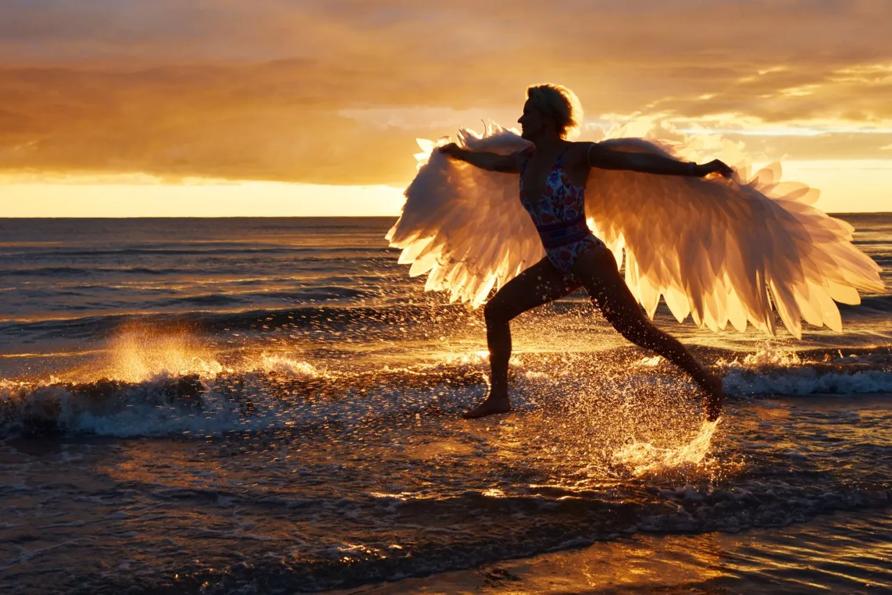 Osoba robiąca zdjęcie zachodu słońca na plaży z telefonem