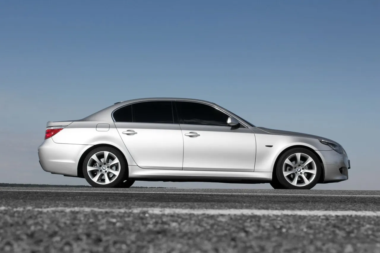 Srebrne BMW E60 535d na tle błękitnego nieba, zaparkowane na drodze.