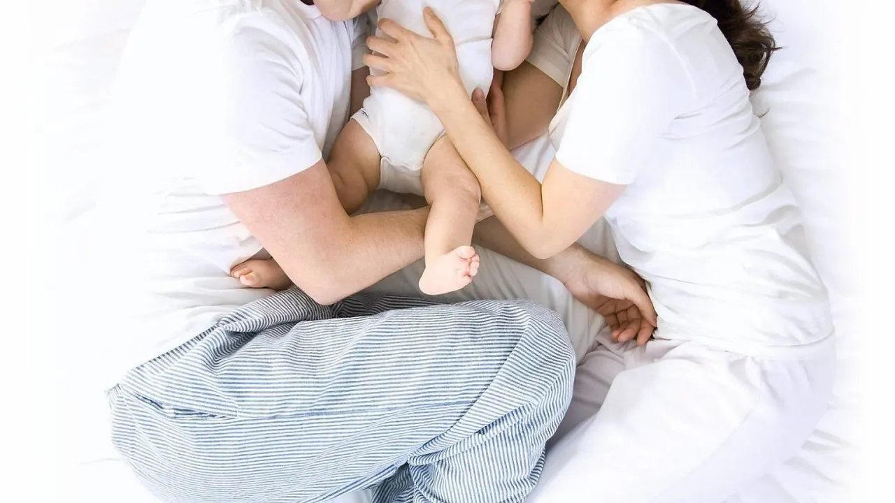 Rodzice z rocznym dzieckiem w łóżku, zamyśleni, ale spokojni