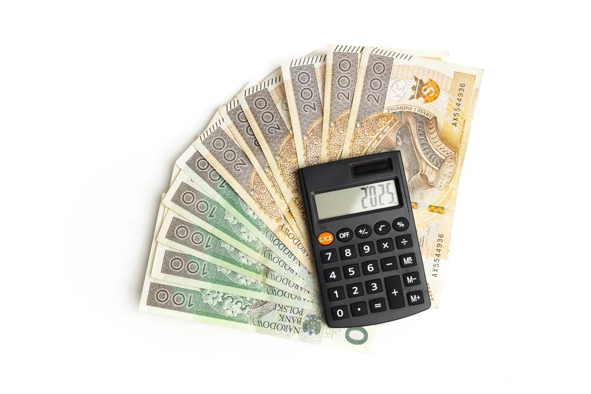 Złot&oacute;wki ułożone wachlarzem i kalkulator pokazujący 2025. Czy to podsumowanie, ile można dorobić na emerytury?