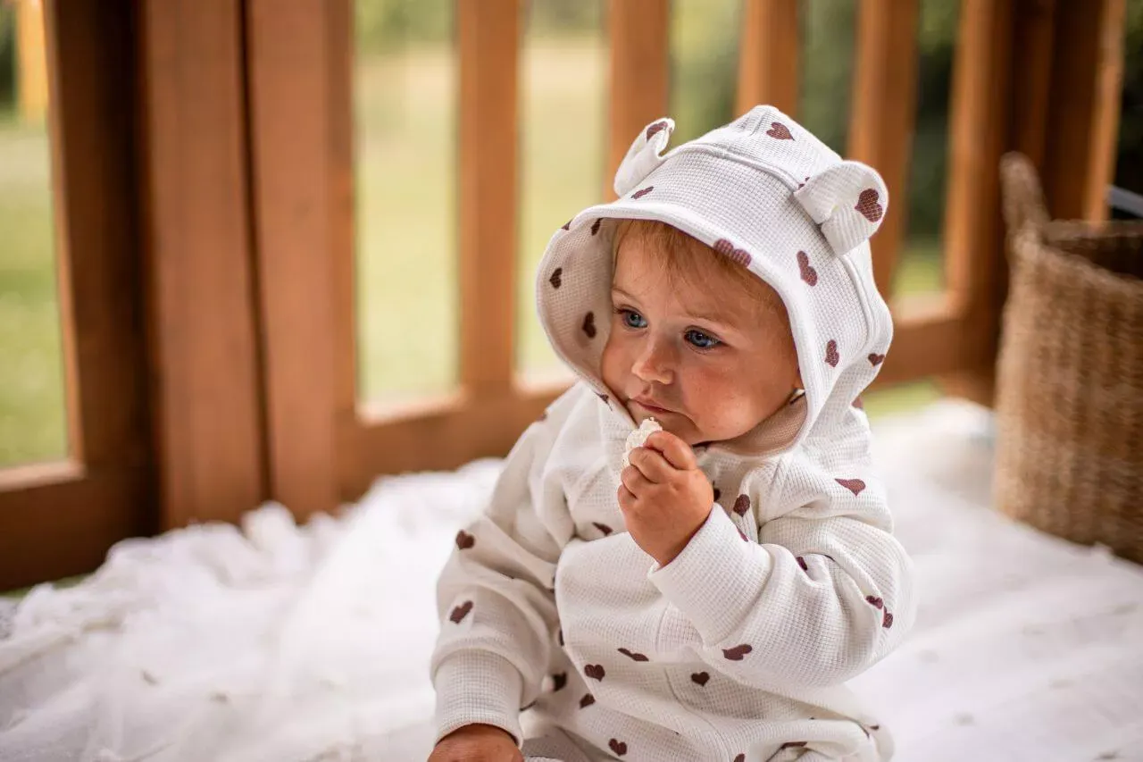 dziecko w kombinezonie zimowym bawi się w śniegu