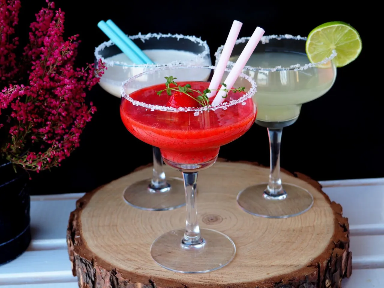 Margarita klasyczna kontra Margarita truskawkowa. Dwa drinki w kieliszkach z solą na brzegu, jeden czerwony, drugi zielony.