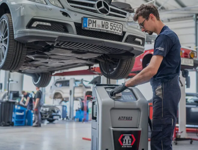 mechanik wymieniający olej w automatycznej skrzyni bieg&oacute;w