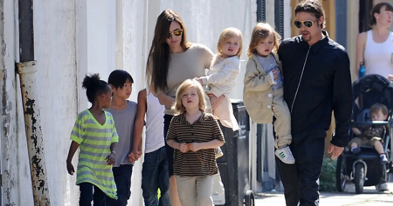 Angelina Jolie z dziećmi, w tym z córką Vivienne, idzie ulicą. Brad Pitt niesie na rękach jedno z dzieci.