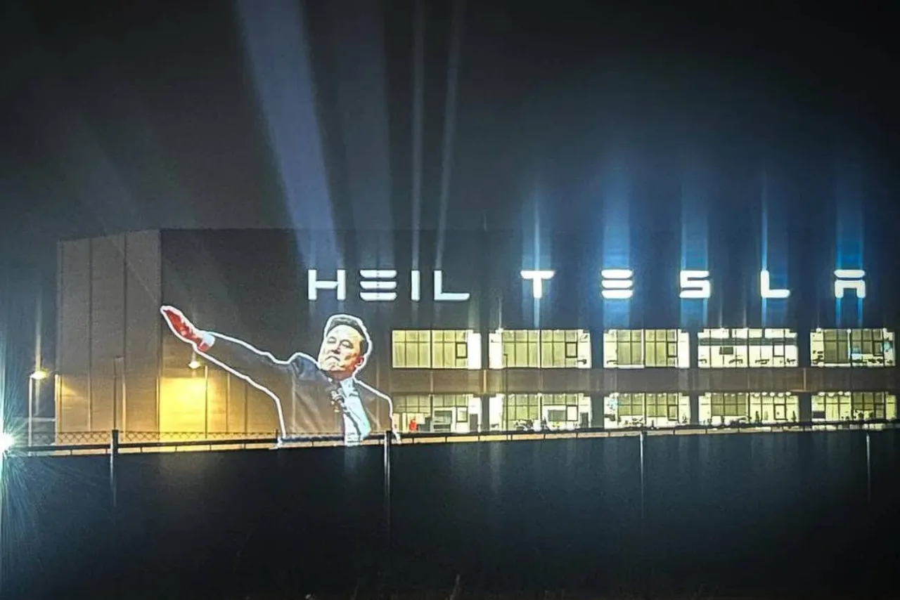 Tesla logo i Elon Musk na tle fabryki