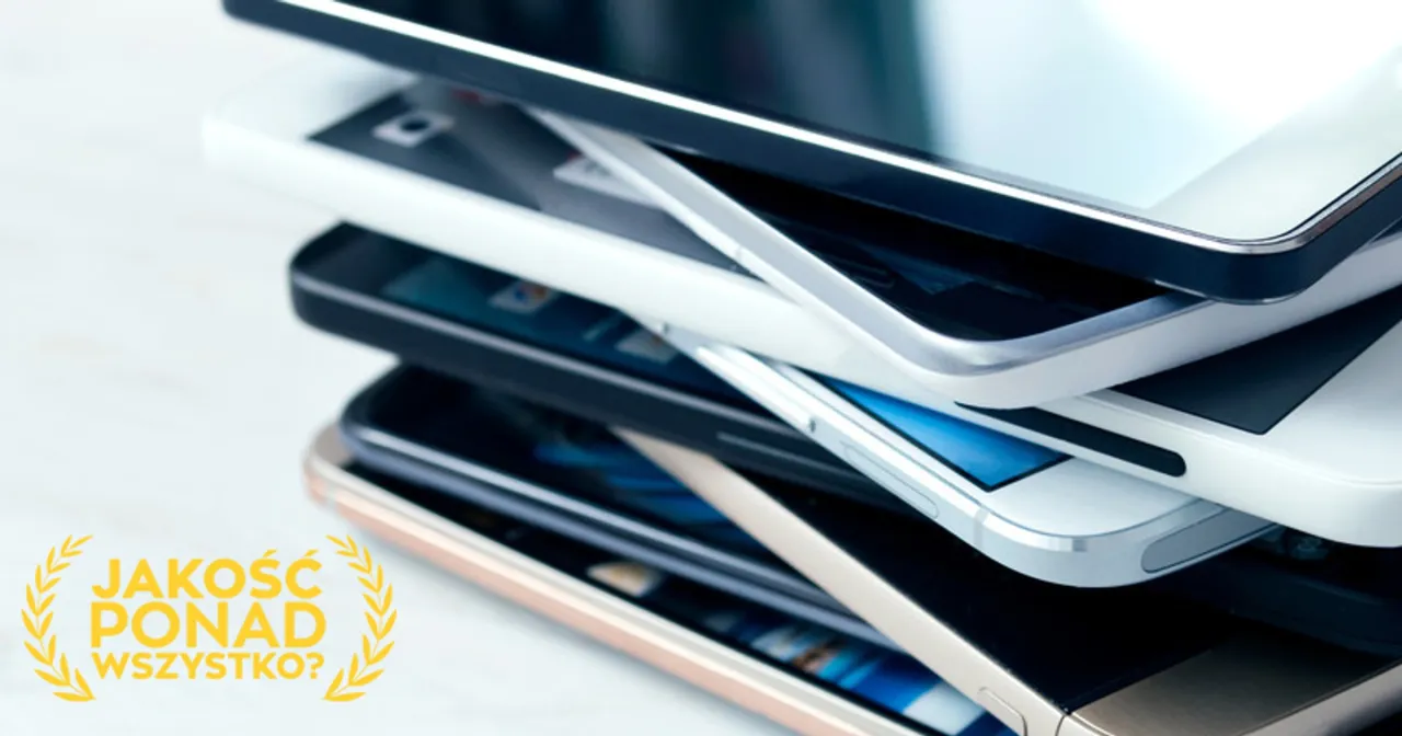 Stos starych smartfon&oacute;w, niekt&oacute;re z widocznym uszkodzeniem mechanicznym, obok napisu 