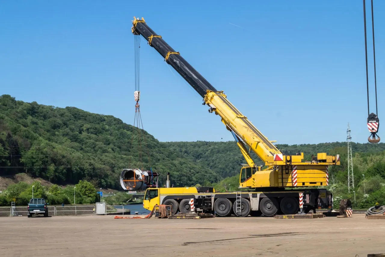 Potężny ż&oacute;łty dźwig z przeciwwagami i stabilnymi podporami zapewnia r&oacute;wnowagę, dlatego dźwig się nie przewraca, podnosząc duży element.