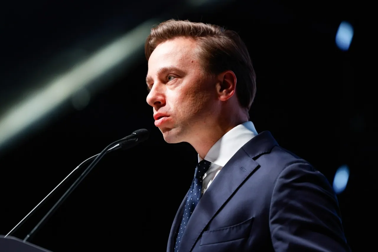 Mężczyzna w garniturze przemawia do mikrofonu. Nie wiadomo, ile lat ma Bosak, ale wygląda na dojrzałego polityka.