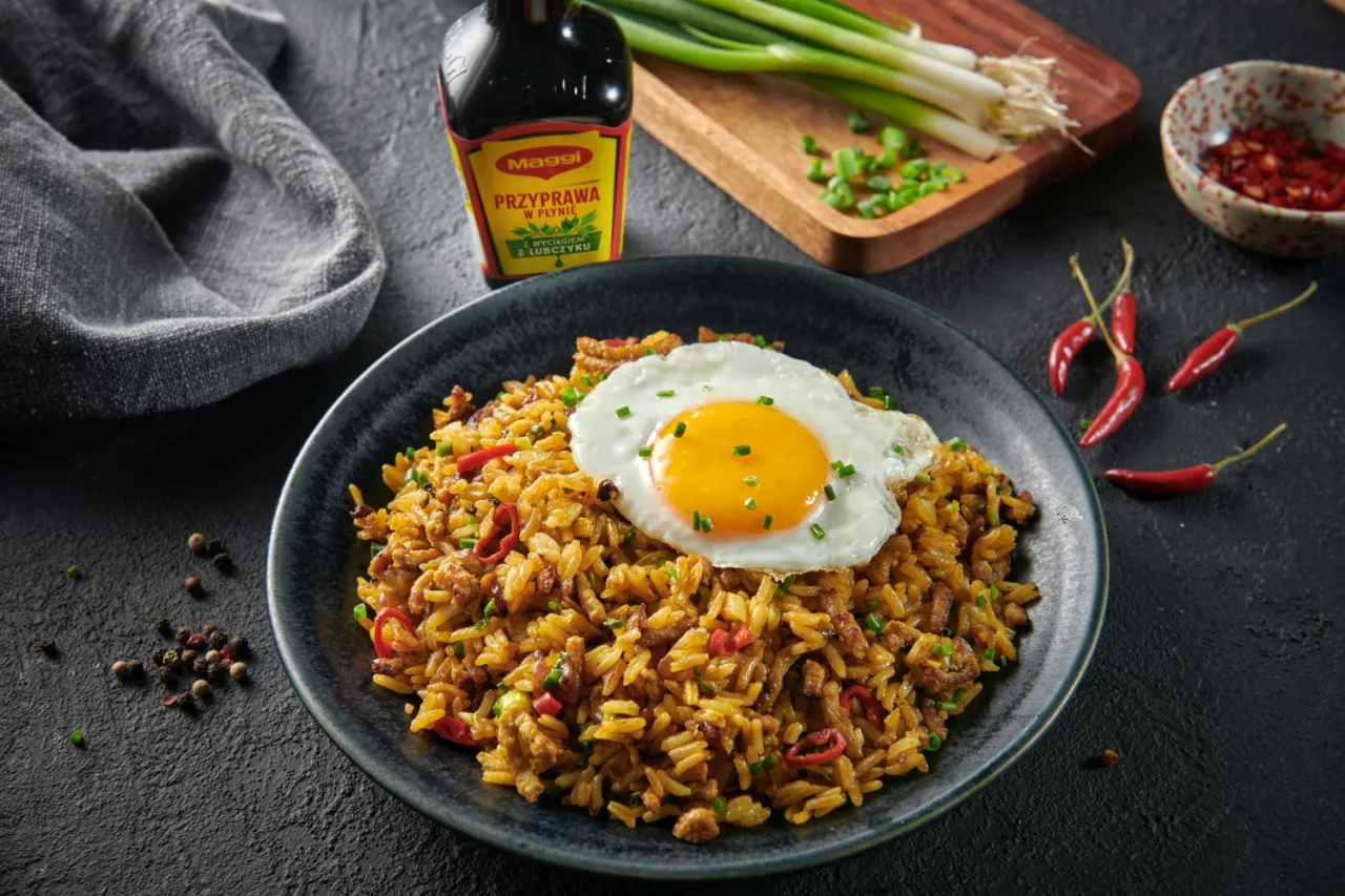 Pyszne nasi goreng z jajkiem sadzonym, doprawione sosem Maggi. Obok papryczki chili i szczypiorek.