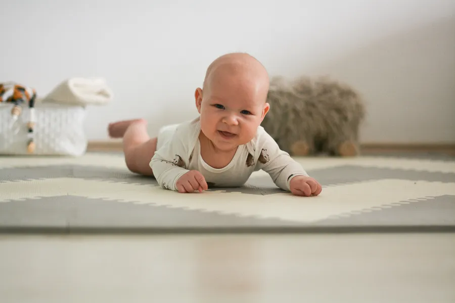 rodzic bawiący się z niemowlęciem na macie edukacyjnej