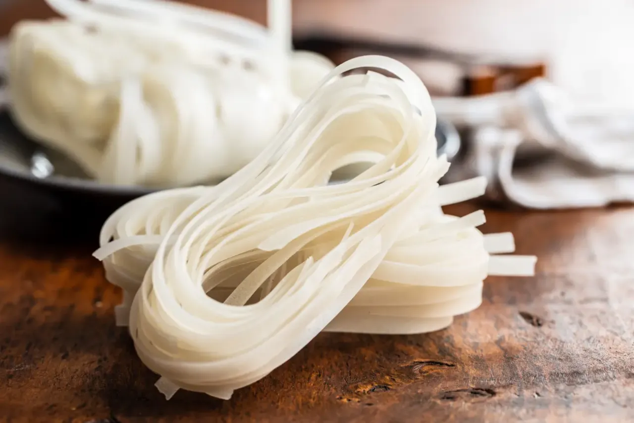 Plastry białego makaronu ryżowego, gotowe do przygotowania pysznego dania. Ryż vs makaron - wybór należy do Ciebie!