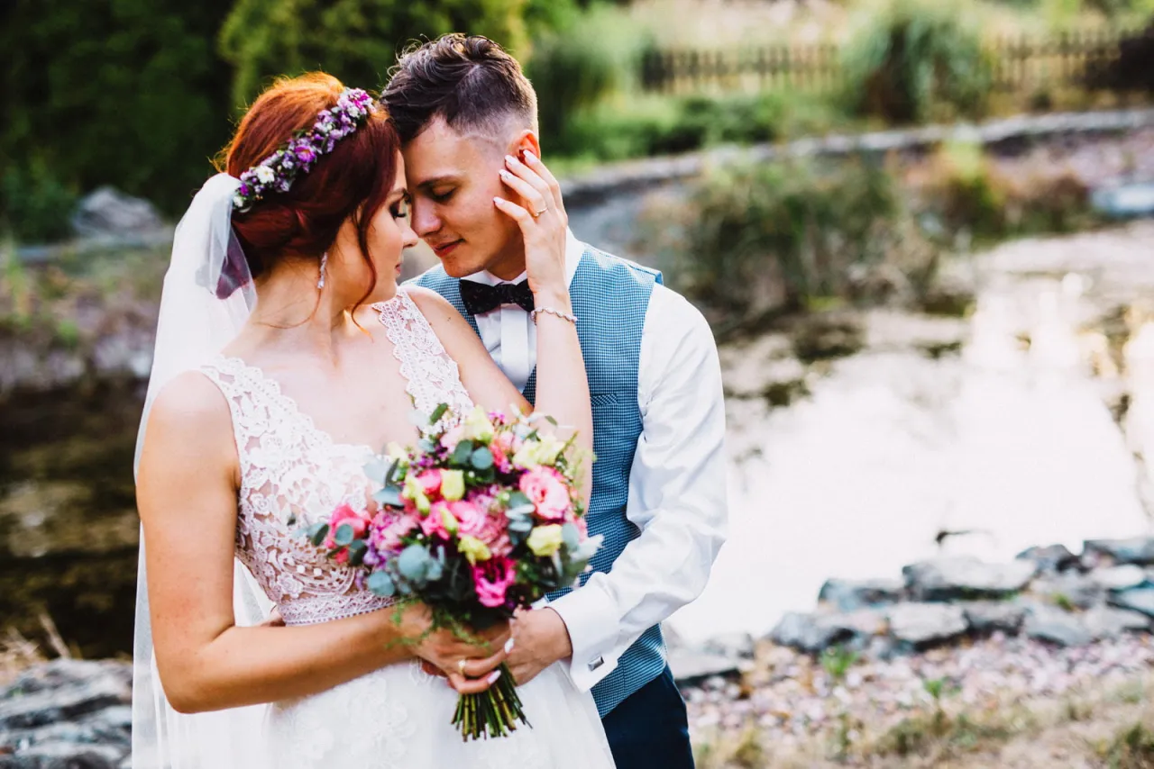 Para młoda w objęciach, ona w białej sukni z bukietem, on w kamizelce. Zastanawiasz się, ile kosztuje fotograf na wesele?