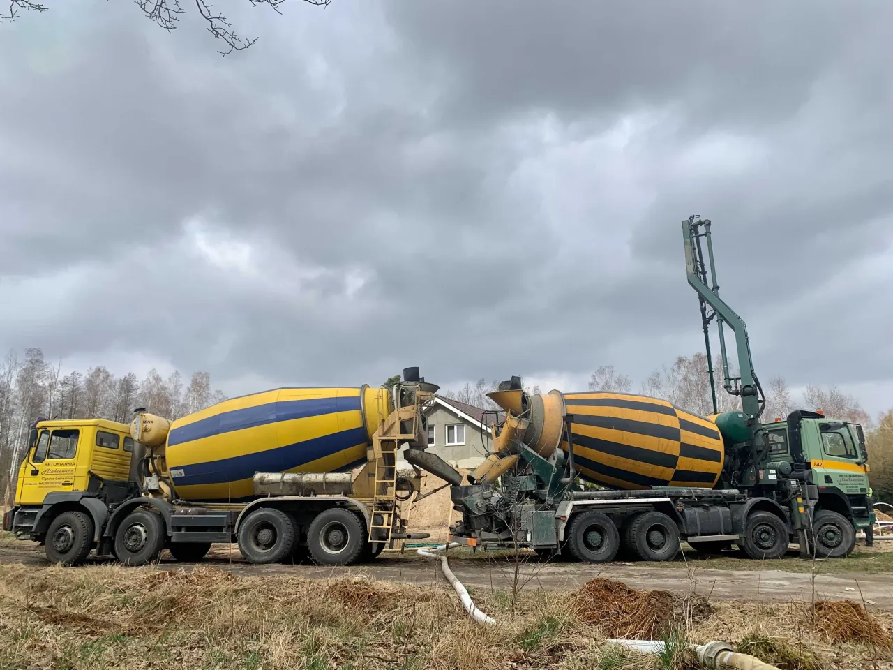 Dwie gruszki betonu, jedna żółto-niebieska, druga żółto-czarna, czekają na placu budowy.