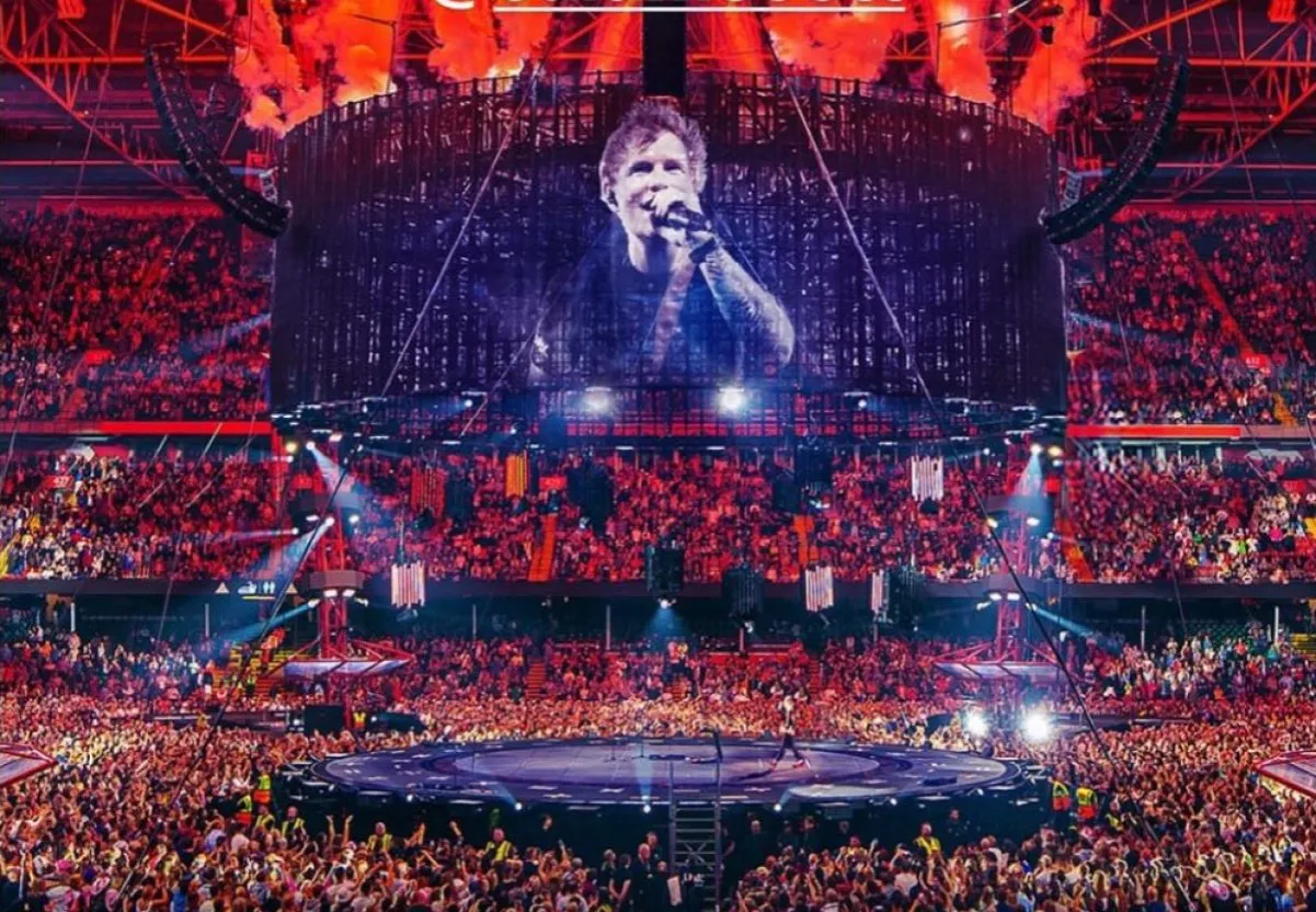 Ed Sheeran na scenie stadionu, tłumy ludzi, pirotechnika. Zastanawiasz się, ile Ed Sheeran bierze za koncert?
