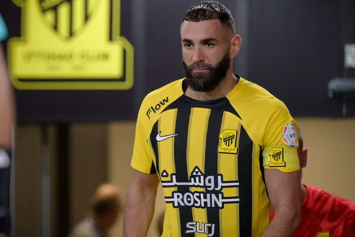 Karim Benzema w ż&oacute;łtej koszulce z czarnymi pasami, zastanawia się, ile zarabia.