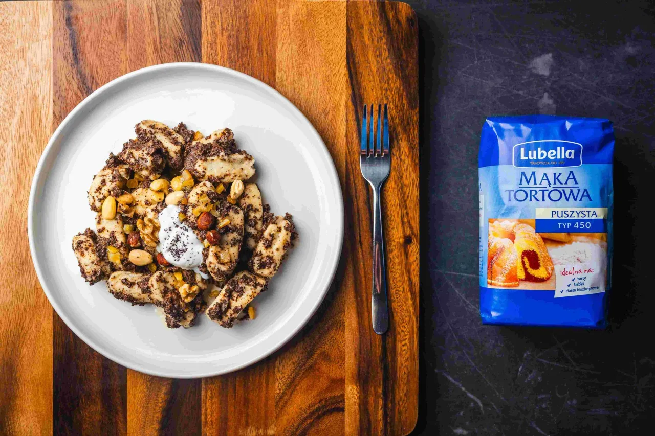 Pyszne kluski z makiem i orzechami, kt&oacute;re można zrobić z ciasta na pierogi. Podane z kleksem śmietany.