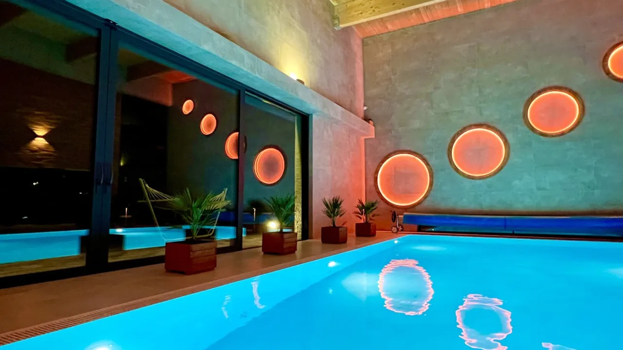 Nowoczesny spa na Śląsku z basenem, oświetlonym pomarańczowymi kręgami na ścianach. Relaks w luksusowym otoczeniu.