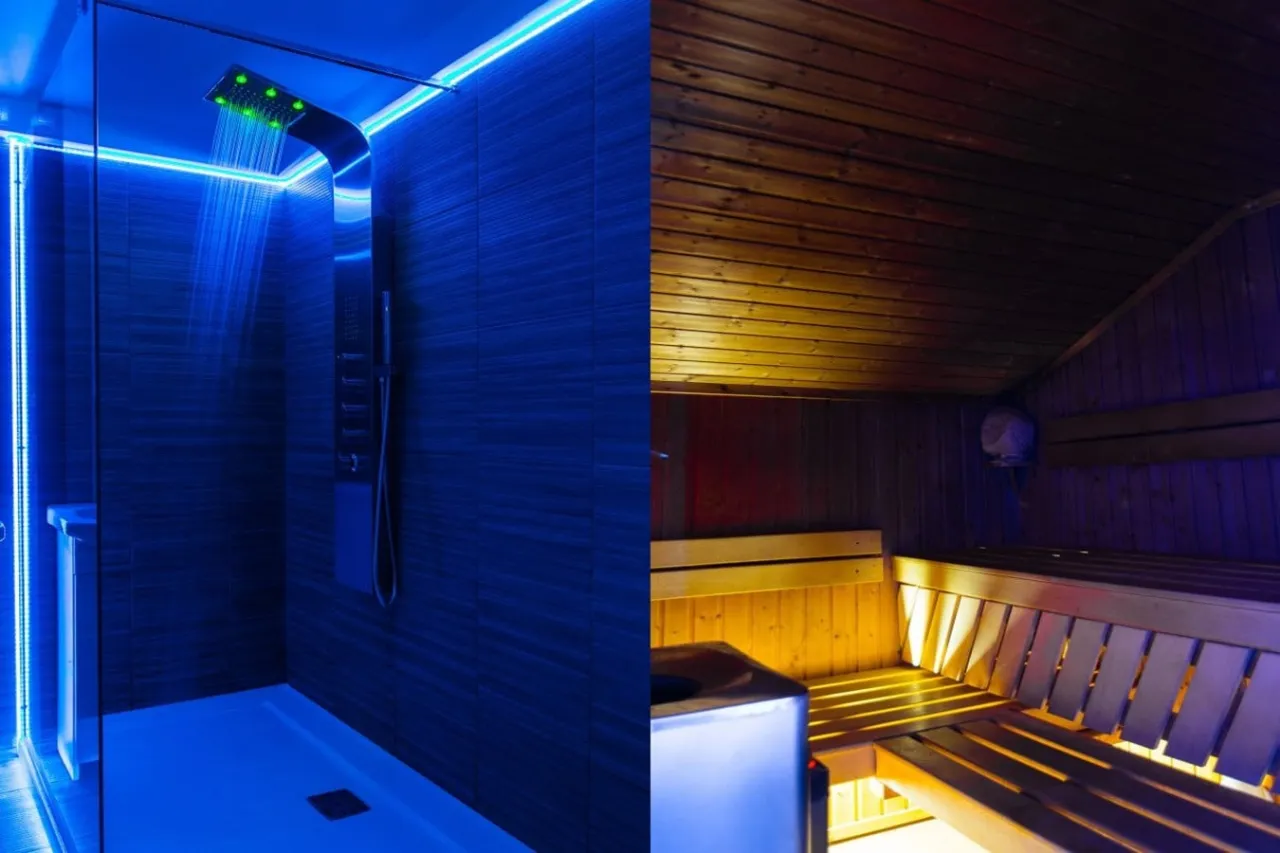 Nowoczesny prysznic z niebieskim podświetleniem i tradycyjna sauna z drewnianymi ławami. Idealne miejsce na relaks w spa pod Poznaniem.