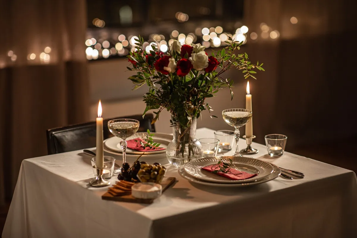 Stół nakryty na romantyczną kolację w domu. Świece, kwiaty i kieliszki tworzą nastrój. Co ugotować?