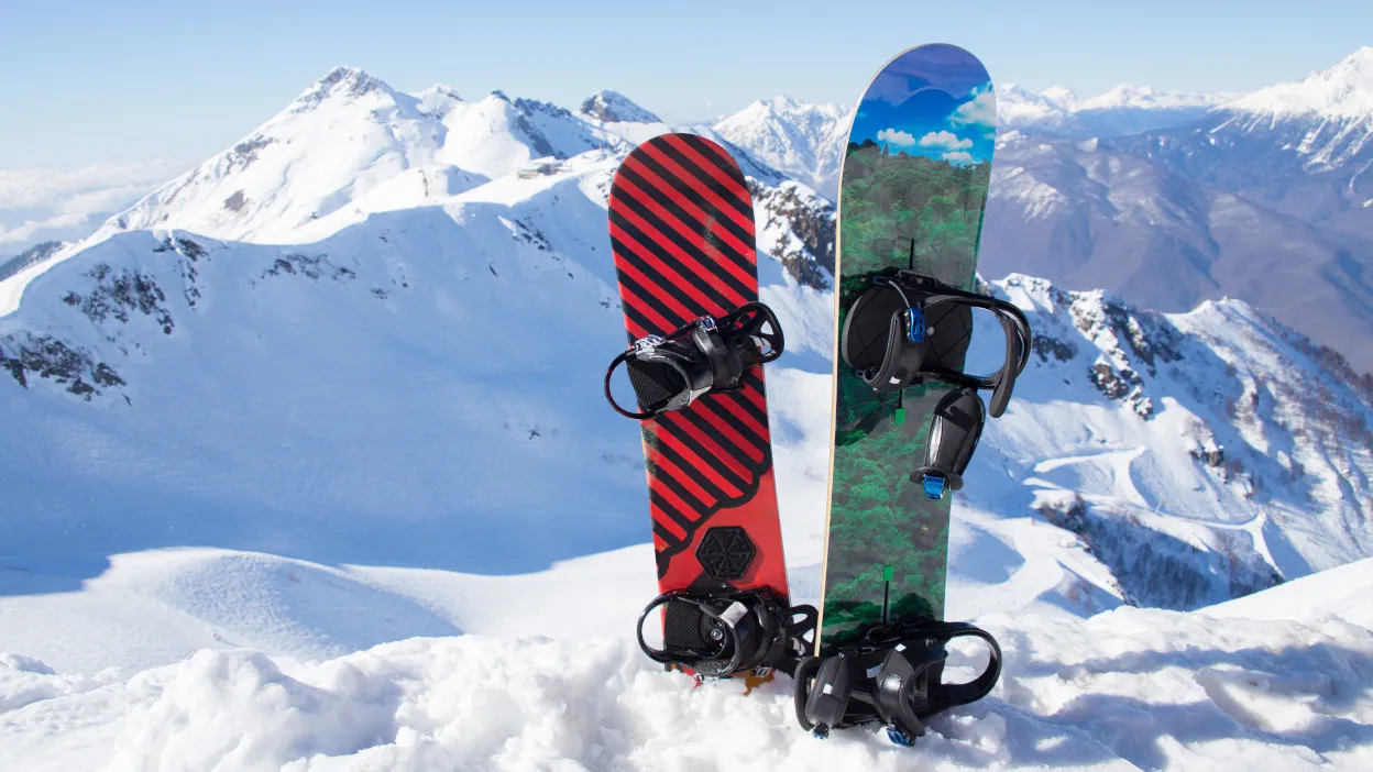 różne deski snowboardowe na tle gór