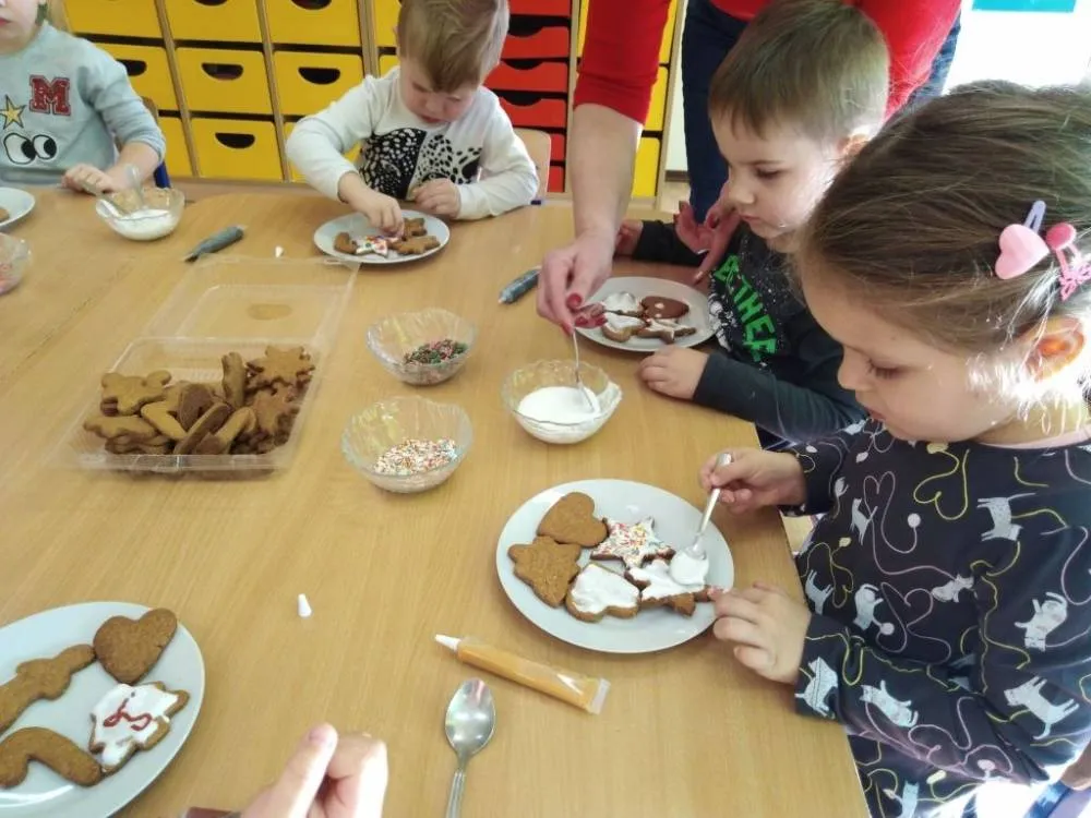 dzieci dekorujące pierniczki świąteczne w przedszkolu